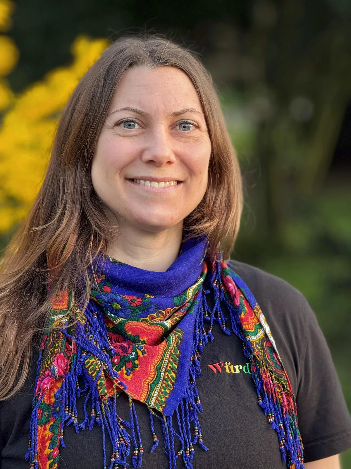 Berit Kranz lächelt, mit einem bunten Schal, im Grünen